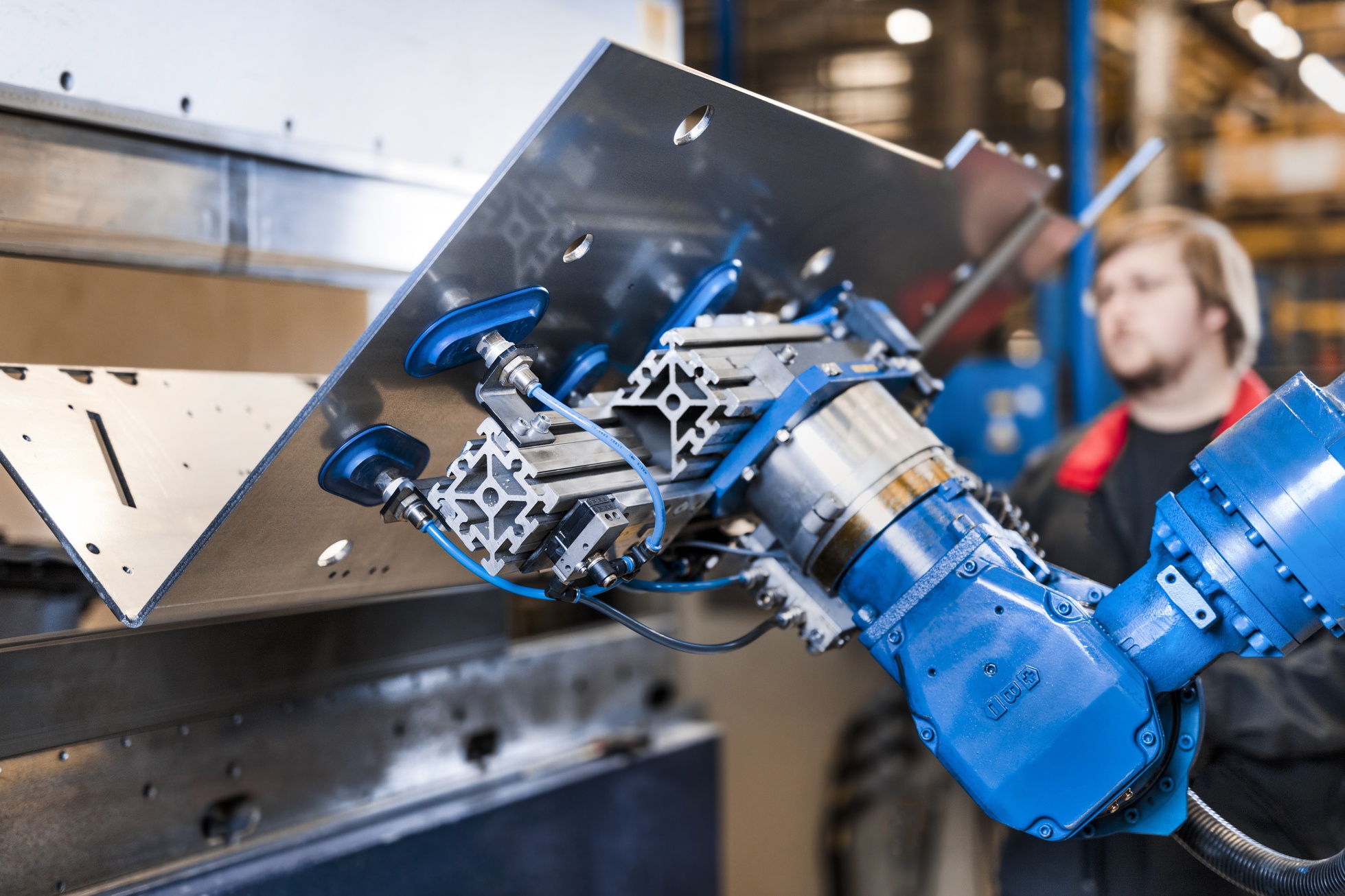 Man aan het werk in een productieomgeving met een robotarm